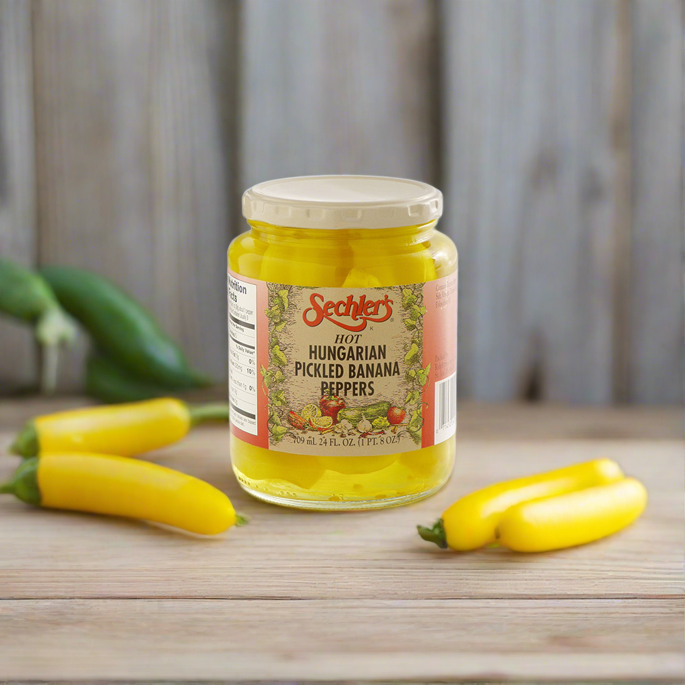 Jar of Hot Hungarian Banana Peppers on kitchen countertop with fresh banana peppers.