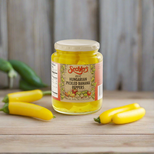 Jar of Hot Hungarian Banana Peppers on kitchen countertop with fresh banana peppers. 