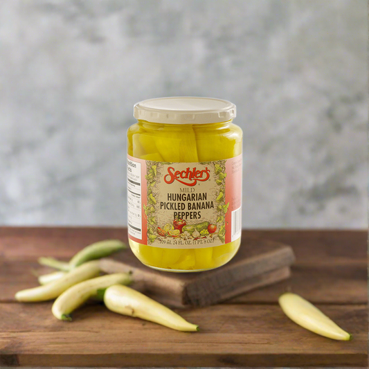 Jar of Mild Hungarian Banana Peppers on kitchen countertop surrounded by fresh banana peppers. 
